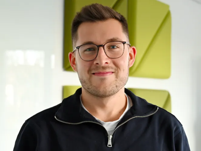 Ein Mann mit Brille vor einer Wand