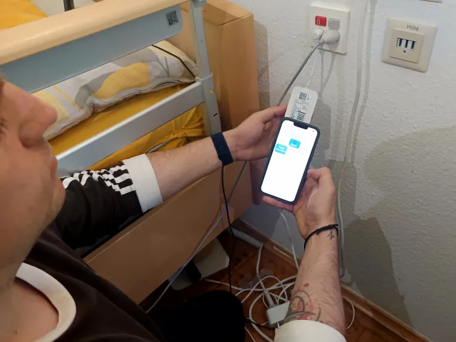 Ein Mann mit einem Handy in der Hand programmiert ein Gerät.