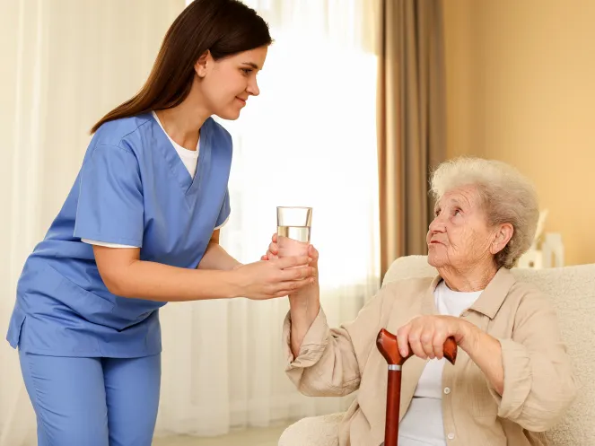 Pflegefachkraft gibt alter Frau ein Glas Wasser