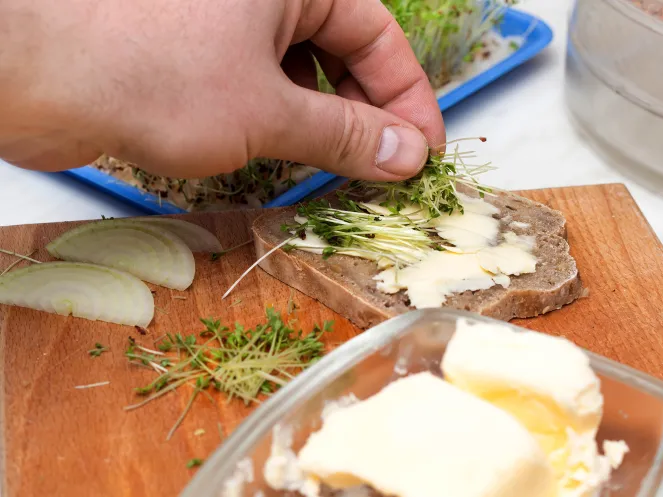 Männliche Hände, die ein Brot schmieren