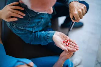 Pflegebedürftiger mit Tabletten in der Hand.