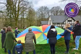 Frauen und Kinder machen eine Übung mit dem Schwungtuch und einem Ball