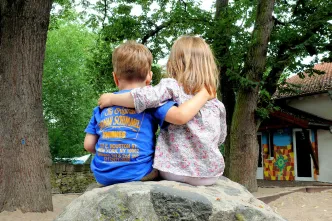 Kinder sitzen auf einem Stein