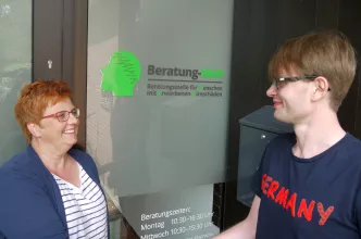 Frau und junger Mann vor Eingang der Beratungsstelle