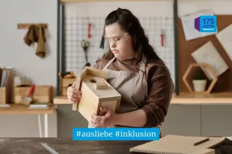 Eine junge Frau stellt in einer Werkstatt für Menschen mit Behinderungen ein Vogelhaus her.