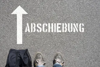 Füße vor dem Schriftzug "Abschiebung" auf dem Boden 