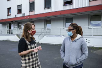 Amelie Ohren von der Diakonie Düsseldorf berät eine Frau unter freiem Himmel in einer städtischen Flüchtlingsunterkunft in Düsseldorf