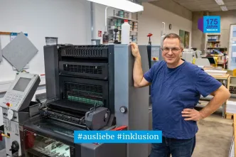 Drucker Andrej Grünberg steht neben einer Druckmaschine.