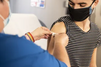 Arzt impft jungen geflüchteten Mann gegen das Corona-Virus