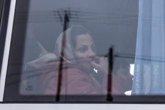 Eine ukrainische Frau sitzt hinter der Scheibe im Bus auf dem Weg nach Deutschland.