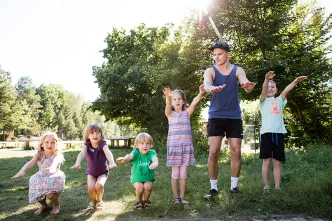 Freiwilliger mit Kindern in einem Feriendorf.