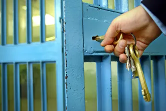 Gefängniswärter schließt Zelle auf.