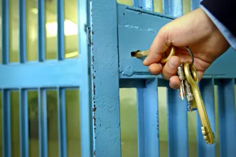 Gefängniswärter schließt Zelle auf.