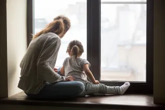 Mutter und Tochter schauen aus einem Fenster.