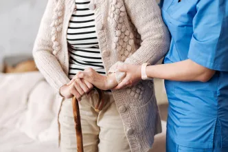 Pflegefachkraft stützt Seniorin.