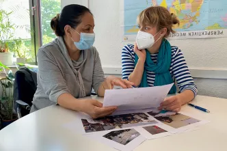 Flüchtlingsberatung: Zwei Frauen sitzen mit Maske am Tisch