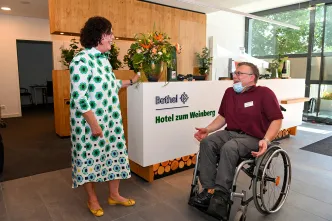 Mitarbeiter Daniel Ibs im Rollstuhl vor der Rezeption im Bethel Hotel zum Weinberg.