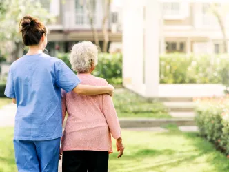 Pflegekraft unterstützt Seniorin