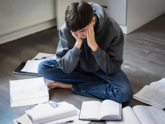 Junge sitzt müde zwischen Büchern auf dem Boden